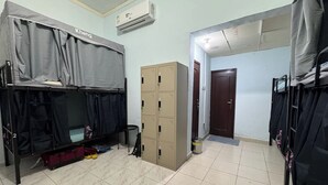 Een slaapzaal met stapelbedden, een kledingkast en een airconditioning.