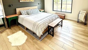 A bedroom with a bed, a nightstand, a bench, a ceiling fan, a window, and a painting on the wall. - Modern Farmhouse w/Privacy, Views and Hot Tub! (GRAND JUNCTION)