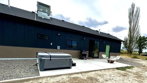 A modern building with a flat roof, a green door, and a patio area with outdoor seating. - Modern Farmhouse w/Privacy, Views and Hot Tub! (GRAND JUNCTION)