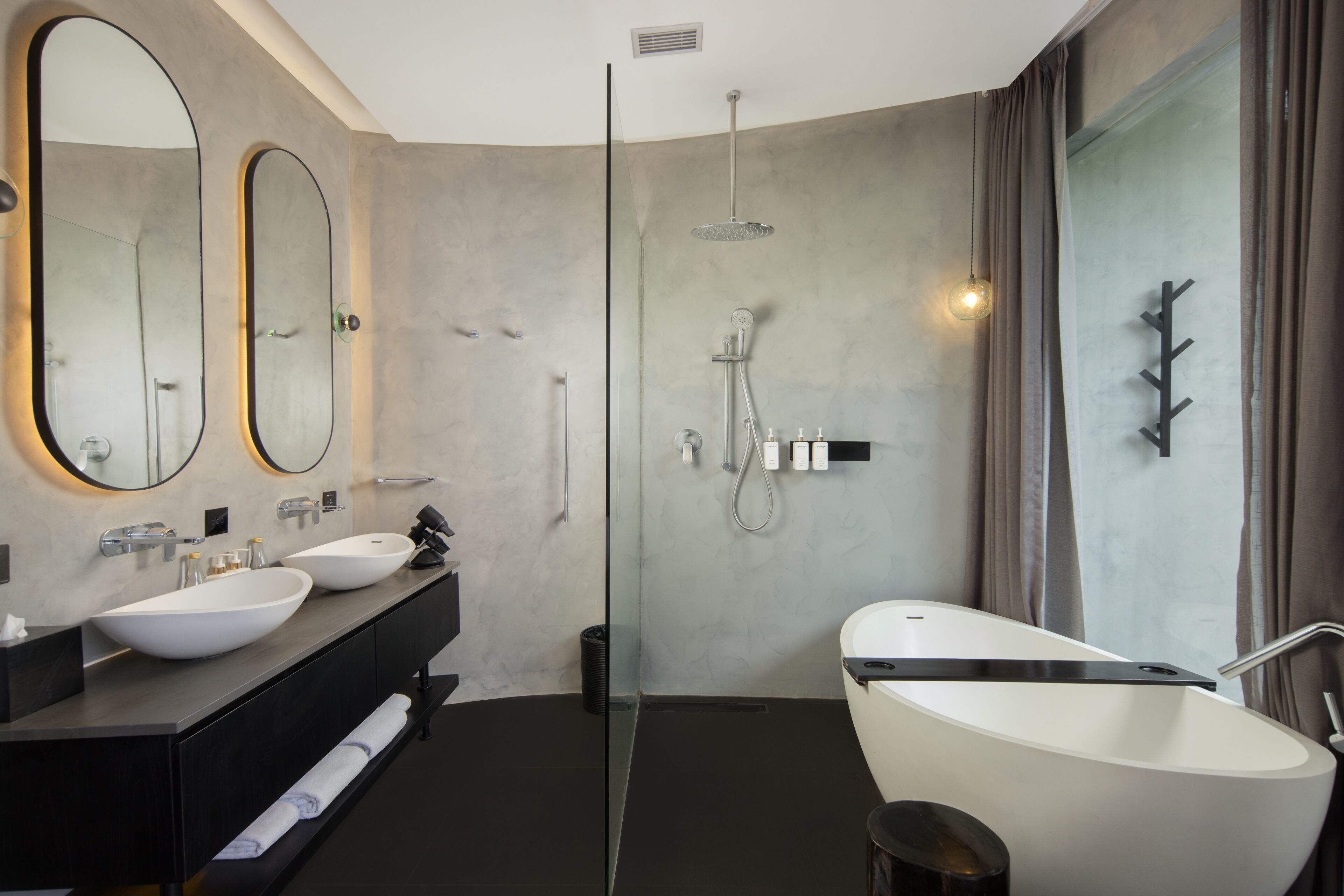 A modern bathroom with a freestanding bathtub, two sinks, and a glass shower enclosure.