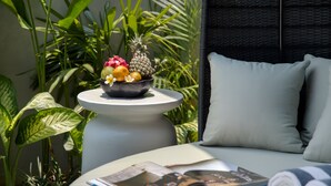 A room with a bed, a small table with a bowl of fruit and flowers, and a magazine. - Je Ne Sais Quoi Seminyak (Seminyak)