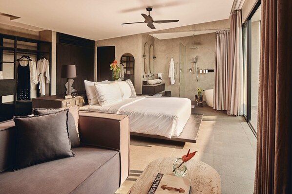 Una habitación de hotel moderna con cama, sofá y una pequeña mesa con un florero.