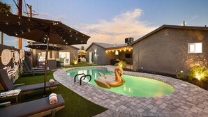 Ein Garten mit Swimmingpool, Liegestühlen und Grillplatz.