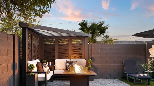 Eine Terrasse mit einer Couch, einem Tisch mit Feuerstelle und einem Sessel.