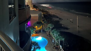 Un hotel con piscina, vista al mar y un balcón con barandilla.