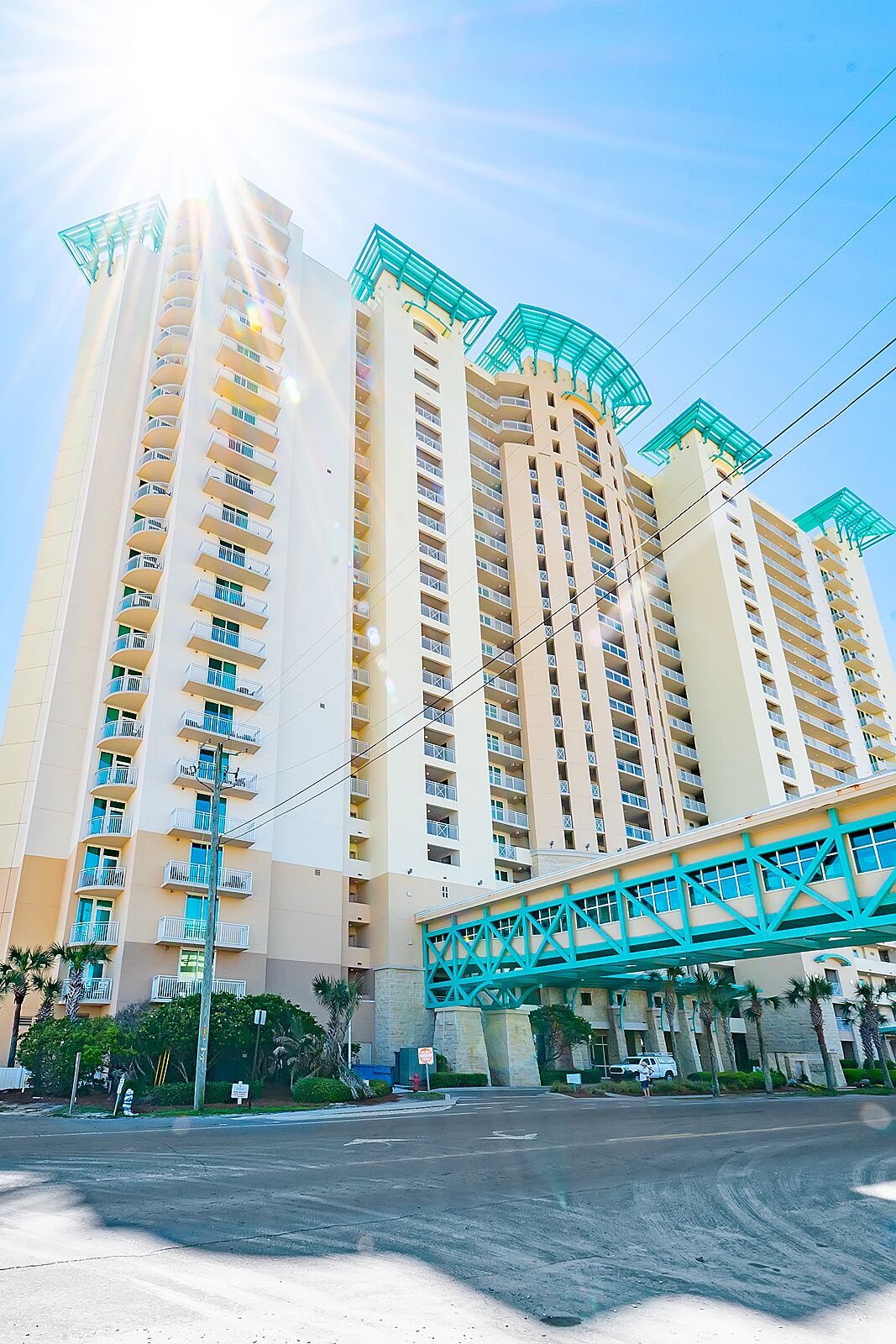 A high-rise hotel with multiple balconies and a pedestrian bridge.
