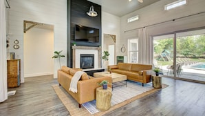 A spacious living room with a fireplace, two sofas, a coffee table, and a large window offering a view of the outdoors.
