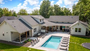 A two-story house with a covered patio area and a swimming pool.