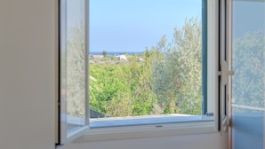Una finestra che si affaccia su un paesaggio verde e un cielo sereno.