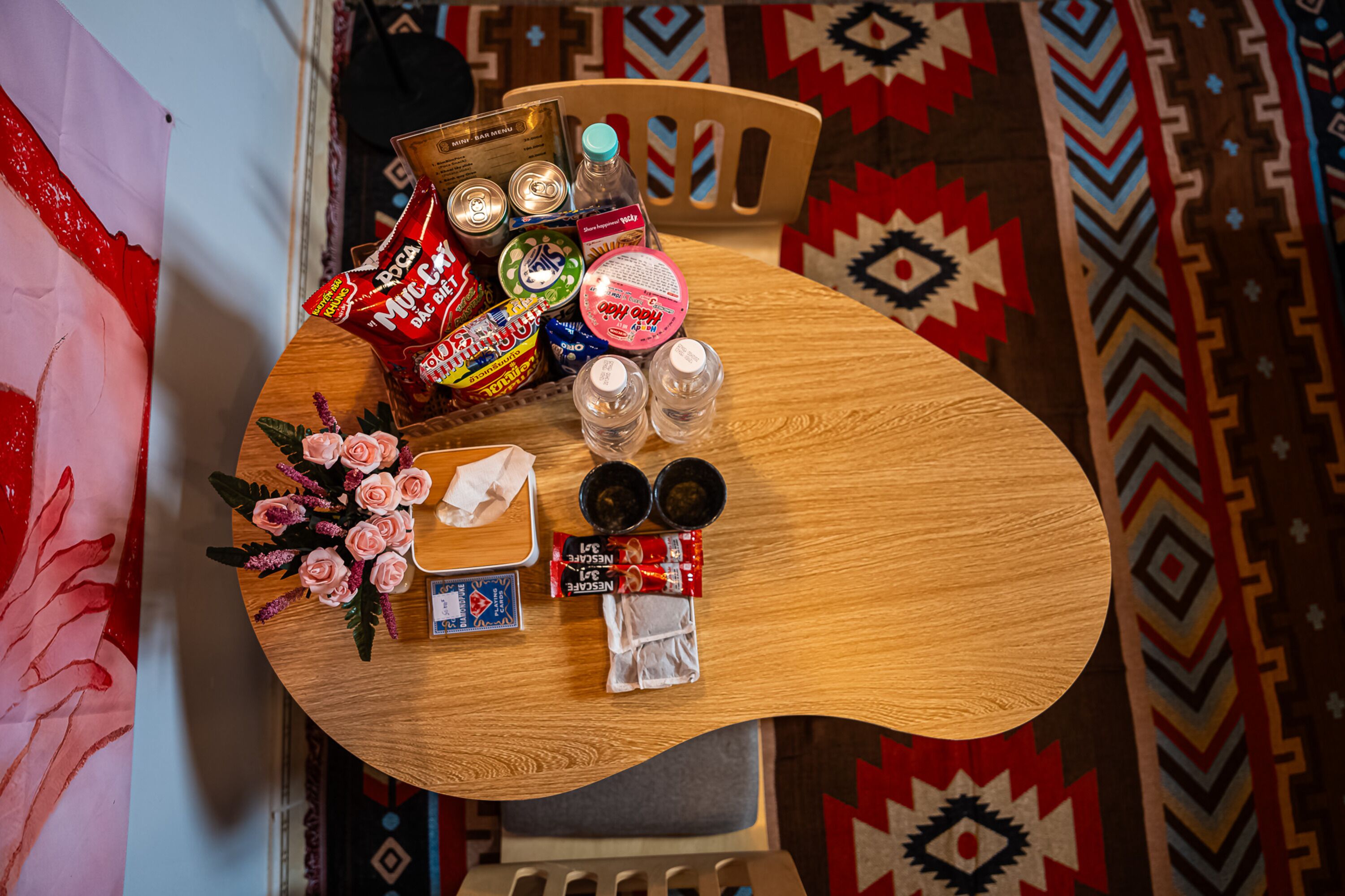 A round wooden table with various items including snacks, a bottle, and a card game.