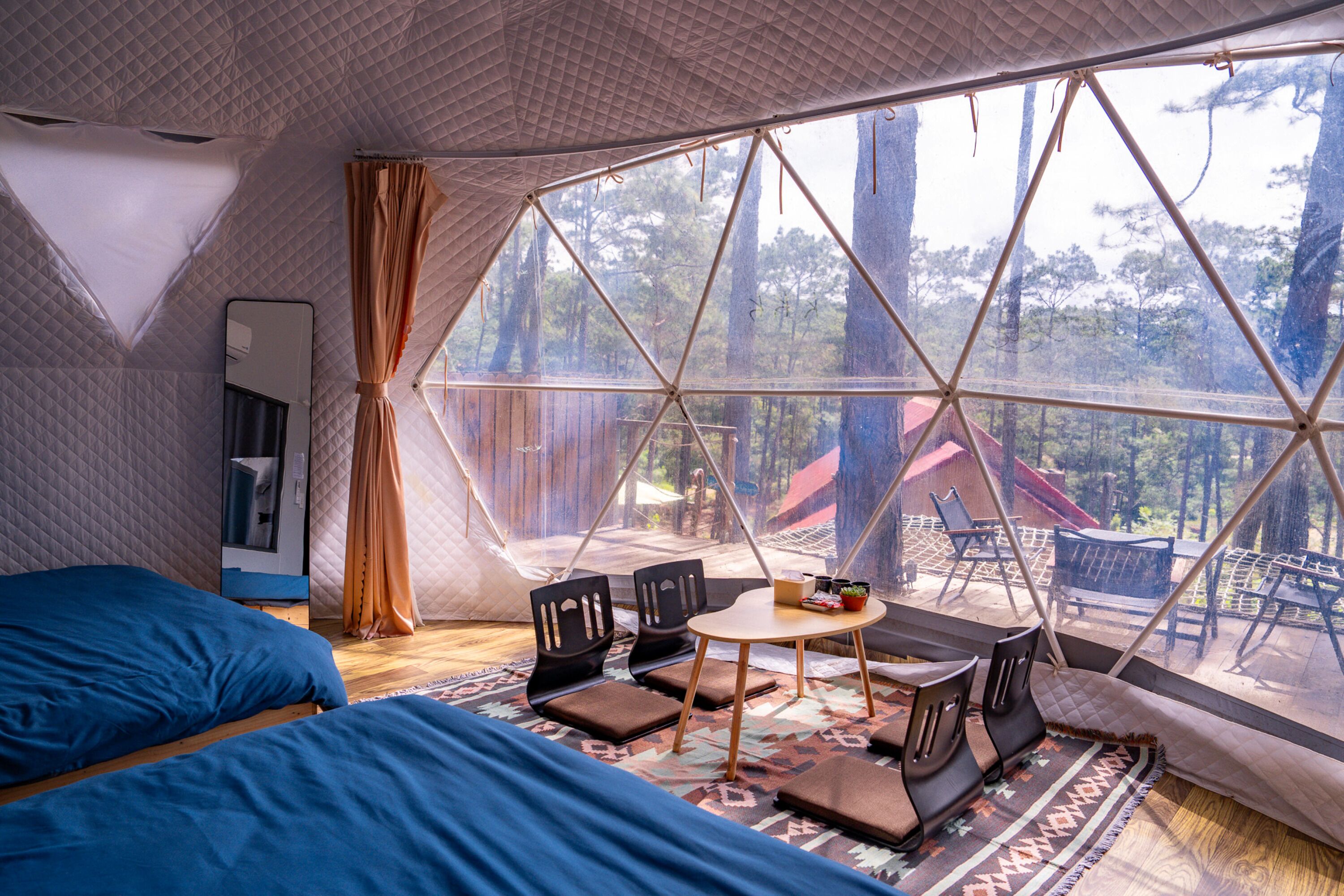 A tented accommodation with a bed, a table, and chairs.