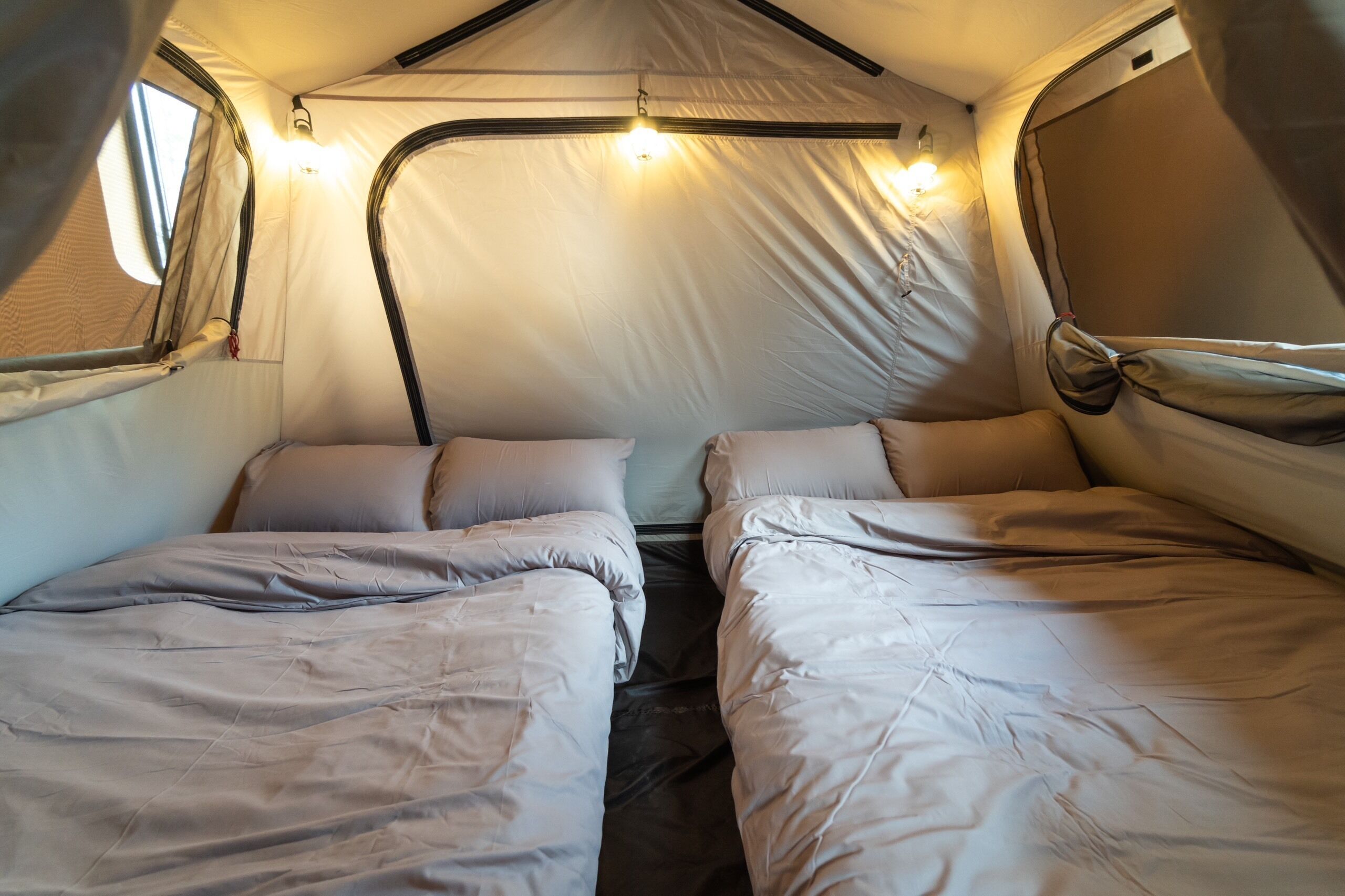 Una carpa con dos camas, cada una con almohadas y mantas.