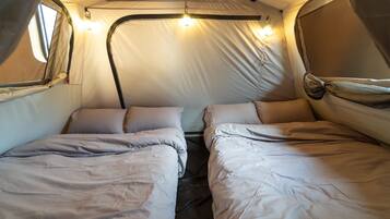 Una carpa con dos camas, cada una con almohadas y mantas.