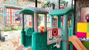 Un espace de jeux pour enfants avec un toboggan, des structures d’escalade et un panier de basket.