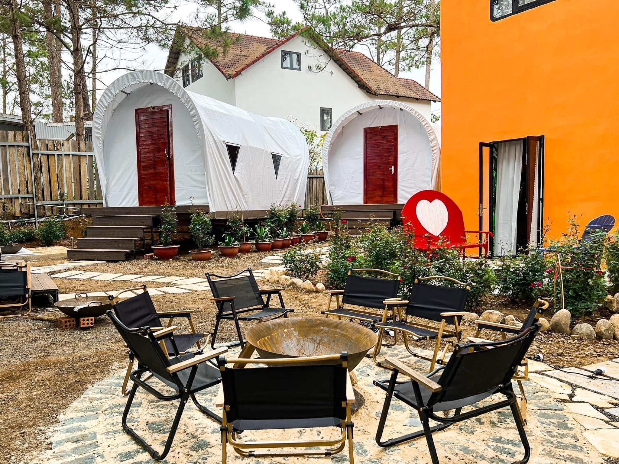 Un patio con dos tiendas de campaña blancas, un letrero rojo con forma de corazón y mobiliario para exteriores.