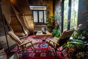 Un espace intérieur accueillant, aménagé comme une tente, avec une table et une lampe, et doté de sièges confortables.