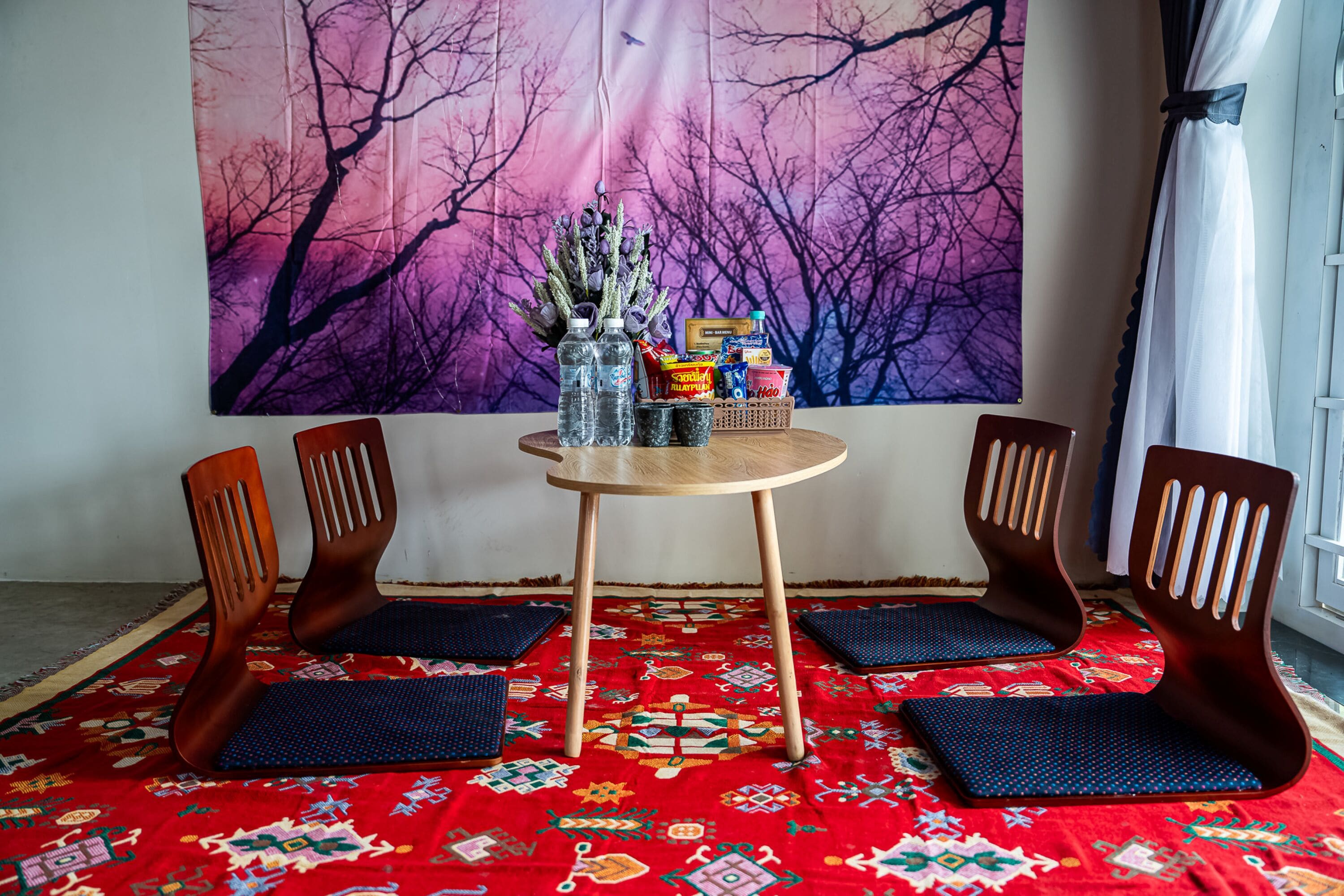 Une pièce avec une table ronde en bois, deux chaises, une tapisserie et un tapis à motifs.