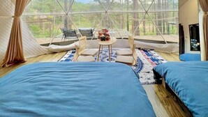 Un hébergement de type tente comprenant deux lits, une petite table et des chaises.