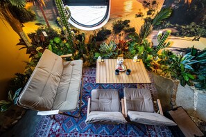Una habitación con un sofá, dos sillones, una mesita y una alfombra estampada.