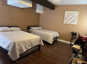 Two single beds with matching headboards and footboards, each covered with a quilted bedspread, sit on a wooden floor.