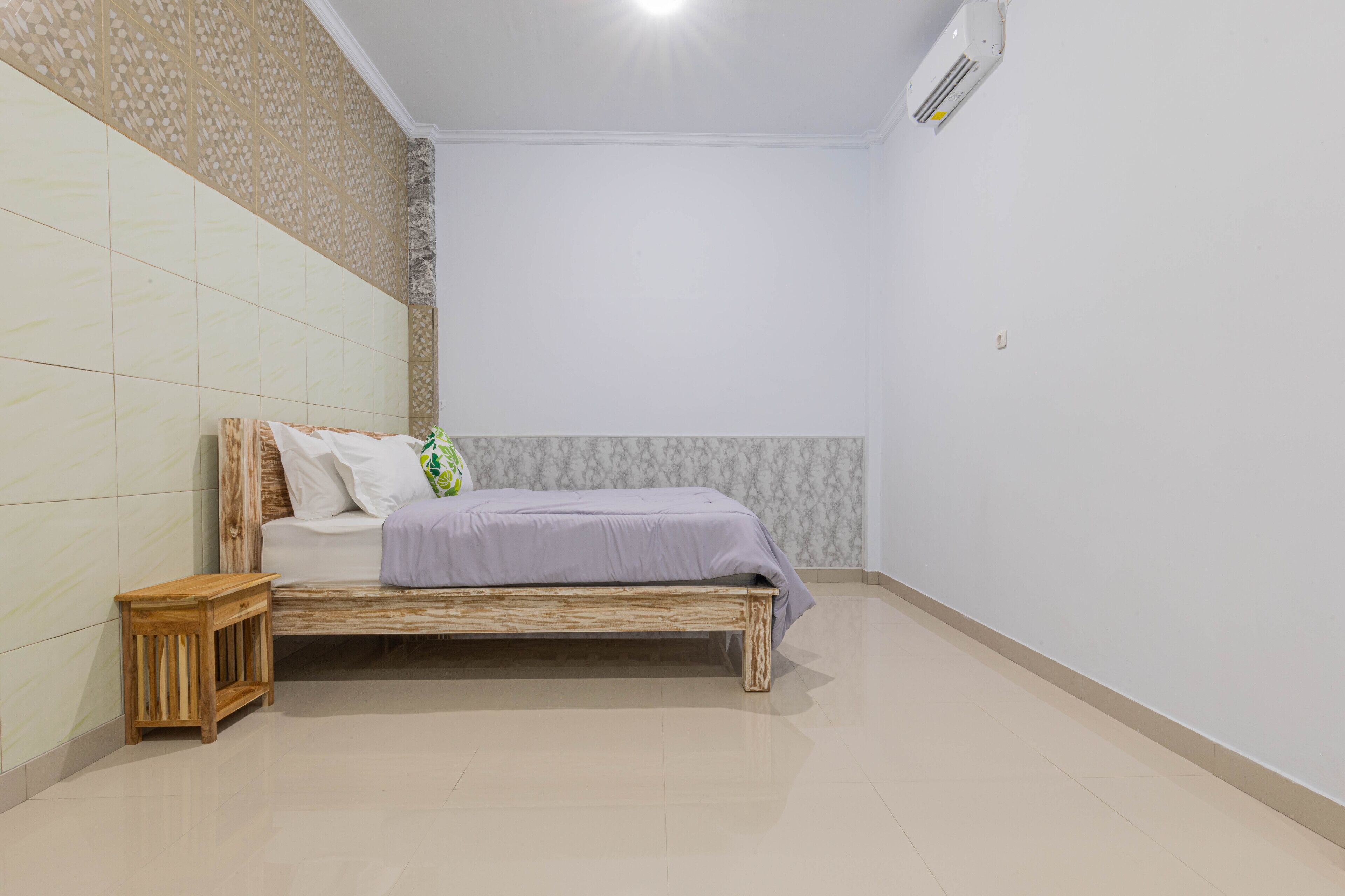 A bedroom with a wooden bed, a small wooden nightstand, and patterned wallpaper on the walls.