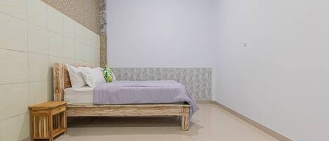 A bedroom with a wooden bed, a small wooden nightstand, and patterned wallpaper on the walls.