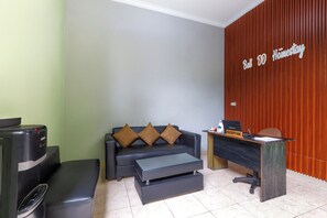 Un área de recepción con mostrador, un sofá con cojines, una mesa de centro y una máquina expendedora.