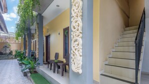 Fachada de um edifício com escadaria, área de estar externa e colunas decorativas.