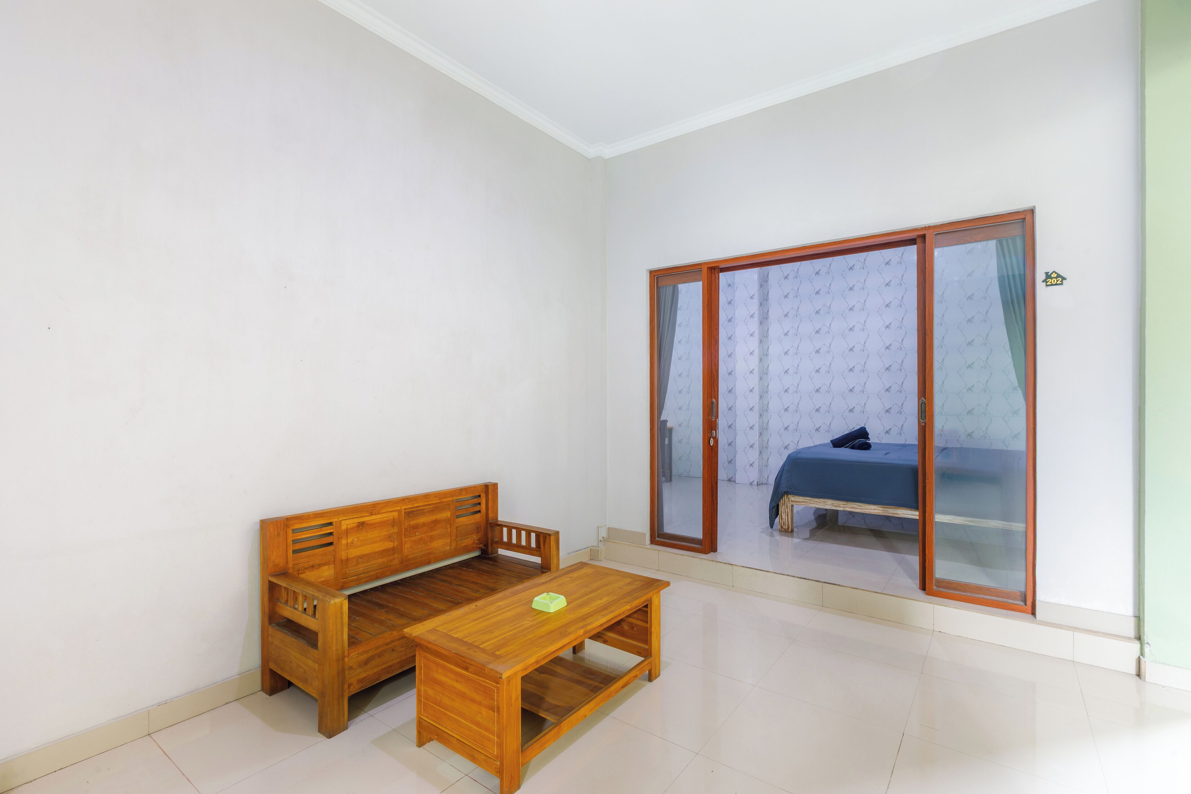 A room with a wooden bench and a table, a sliding glass door leading to a bed.