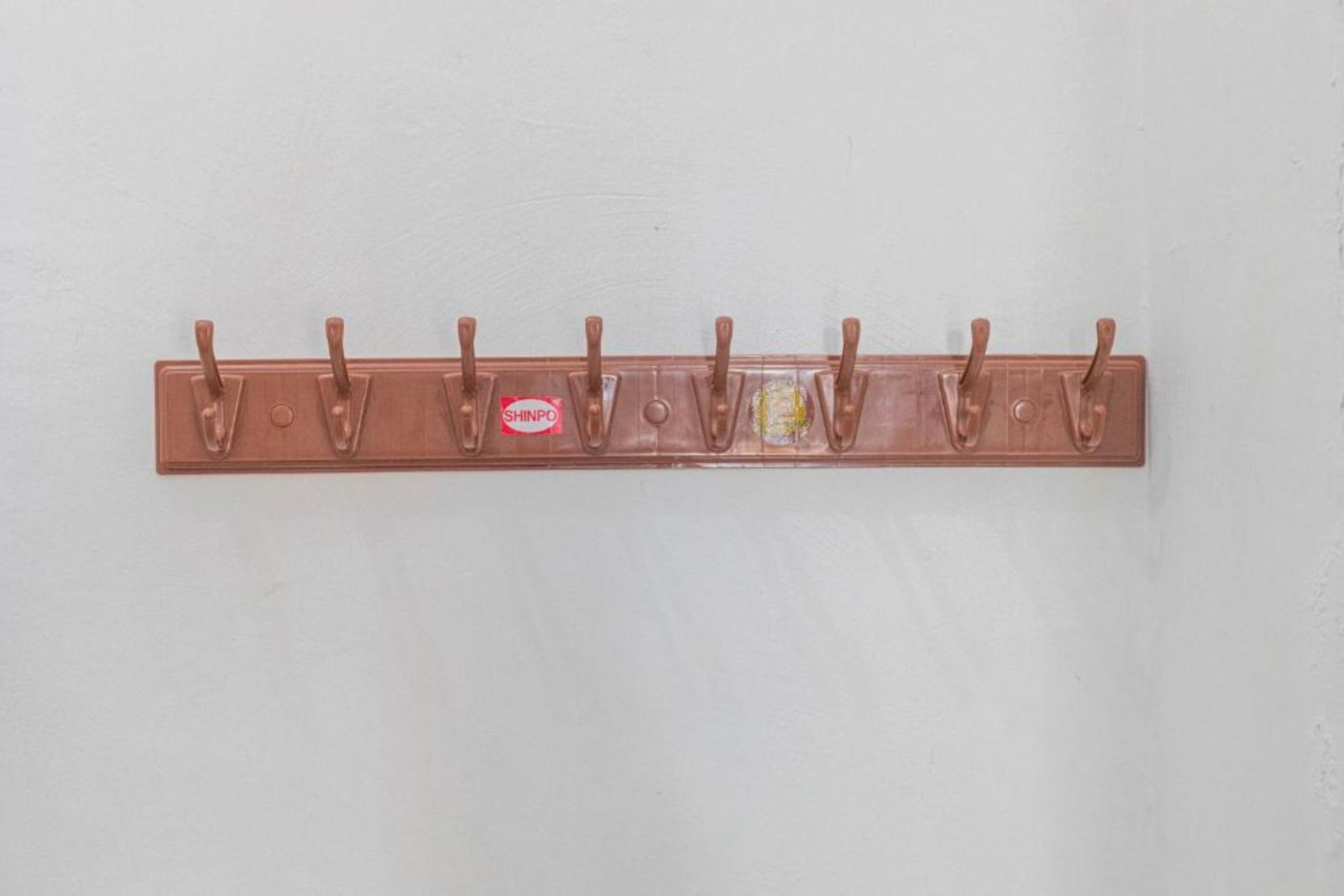 A wall-mounted copper-colored coat rack with six hooks.