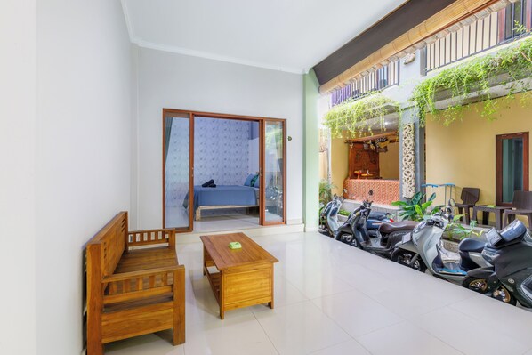 Amplio espacio interior con un banco de madera, una mesita y un sofá. Varias scooters estacionadas afuera.