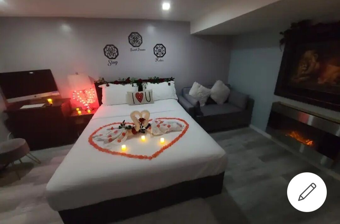 Ein modernes Schlafzimmer mit einem ordentlich bezogenen Bett, einem Fernseher und einem Kamin.
