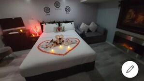 Een moderne slaapkamer met een opgemaakt bed, een televisie en een open haard.