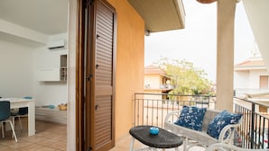 A balcony with a wicker table and chairs, a white desk with a chair, and a closed door. - Apartment 'La Casa Di Terry' with Balcony and Air Conditioning (Acireale)