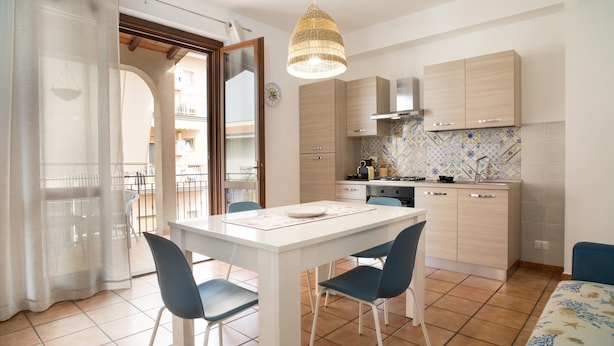 A compact kitchen with a dining table, chairs, and a hanging light fixture. - Apartment 'La Casa Di Terry' with Balcony and Air Conditioning (Acireale)