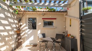 A patio with two chairs, a small table, a window, and a wall-mounted thermometer.