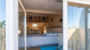 A bedroom with a bed, a desk, a chair, a lamp, and a window.