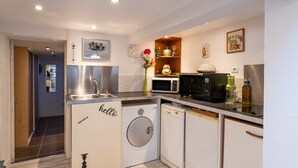 A compact kitchen with a washing machine, dishwasher, microwave, and a small refrigerator.