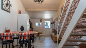 A dining area with a round table, bar stools, and a staircase with a stone wall.