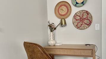 Een moderne kantoorruimte met een houten bureau, een bruine fauteuil en decoratieve geweven borden aan de muur.