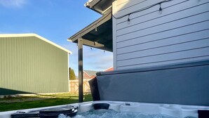 A hot tub with a wooden deck and a house in the background. - Waddle on Inn-Ocean Park Cottage (Ocean Park)
