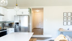A modern kitchen with white cabinets, stainless steel appliances, and a large island. - Waddle on Inn-Ocean Park Cottage (Ocean Park)