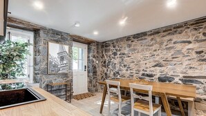 A dining area with a stone wall, wooden table, and chairs.