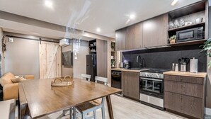 A modern kitchen with wooden cabinets, stainless steel appliances, and a dining area with a wooden table and chairs.