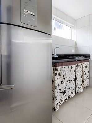 A modern kitchen with a stainless steel refrigerator, a black countertop, and a window above the sink.