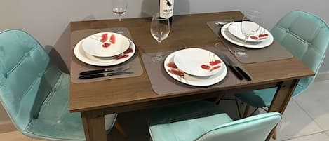 Una mesa de comedor con platos, cubiertos y una botella de vino.