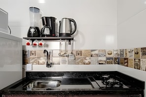 Cozinha com bancada preta, eletrodomésticos de aço inoxidável e painel de azulejos com fotos antigas.
