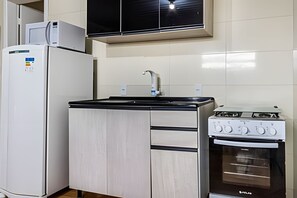 Une cuisine de taille réduite équipée d’un réfrigérateur, d’un évier et d’une cuisinière.