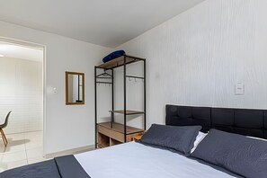 Quarto com cama, guarda-roupa, espelho e uma cadeira.