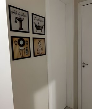 Un mur avec quatre tableaux encadrés, une porte et un interrupteur.